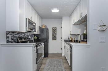 A kitchen with white cabinets and a black refrigerator